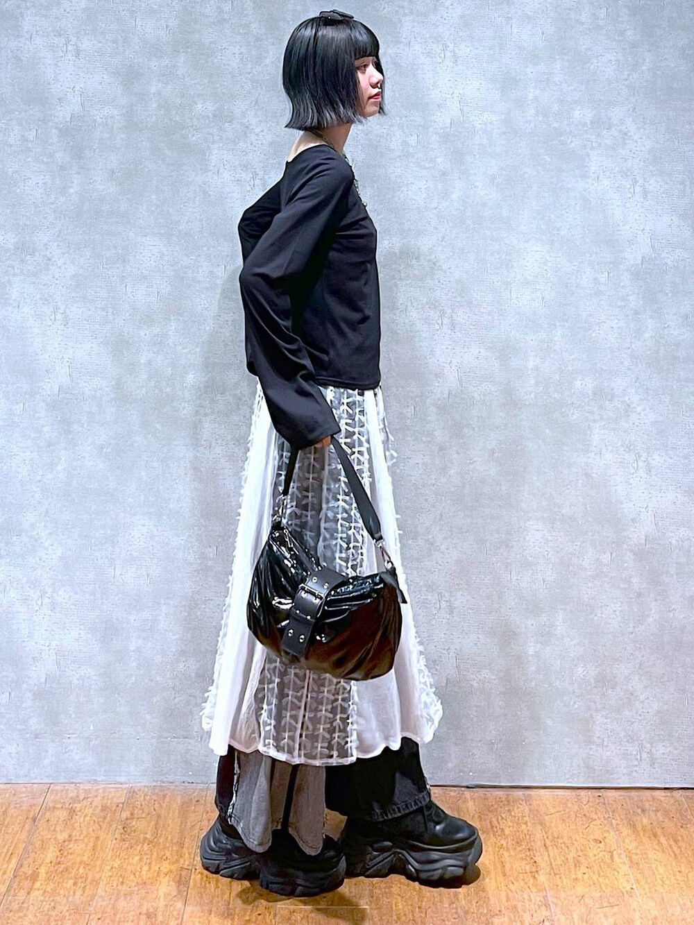 ブラック系のスニーカー、ブラック系のデニムパンツ、ブラック系のショルダーバッグを着用したレディースの夏コーディネートの3枚目の写真