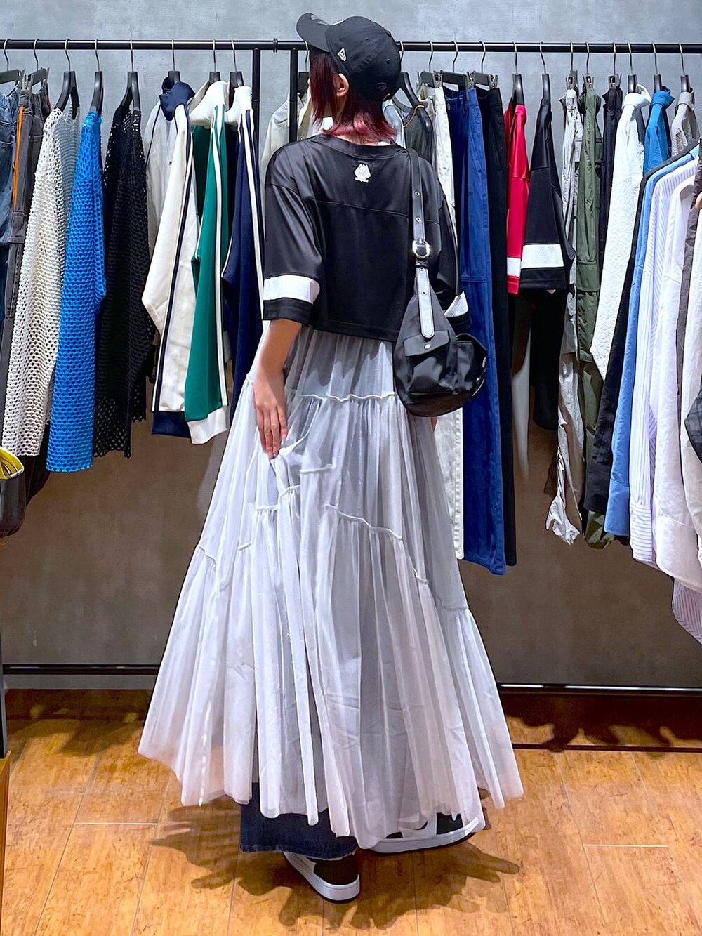 ブラック系のショルダーバッグ、ブルー系のデニムパンツ、ホワイト系のワンピースを着用したレディースの春コーディネートの7枚目の写真