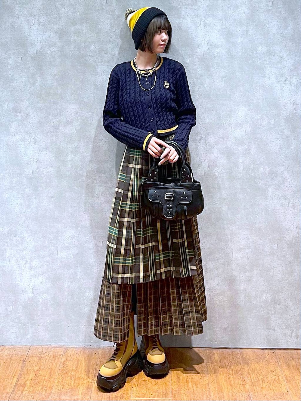 ブラウン系のブーツ、イエロー系のスカート、ブラック系のハンドバッグを着用したレディースの秋コーディネートの3枚目の写真