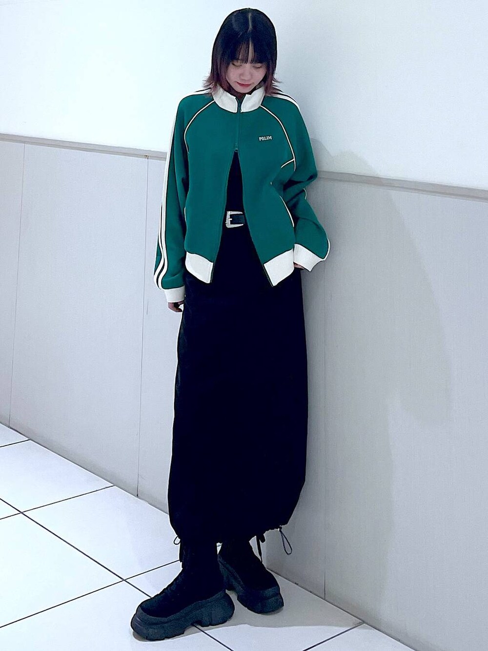 グリーン系のセットアップ、ブラック系のタンクトップ、ブラック系のブーツを着用したレディースの春コーディネートの3枚目の写真