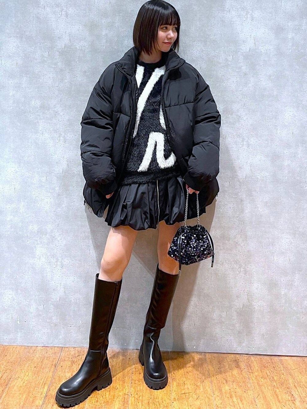 ブラック系のスカート、ブラック系のブーツ、ブラック系のダウンジャケット/コートを着用したレディースの冬コーディネートの4枚目の写真