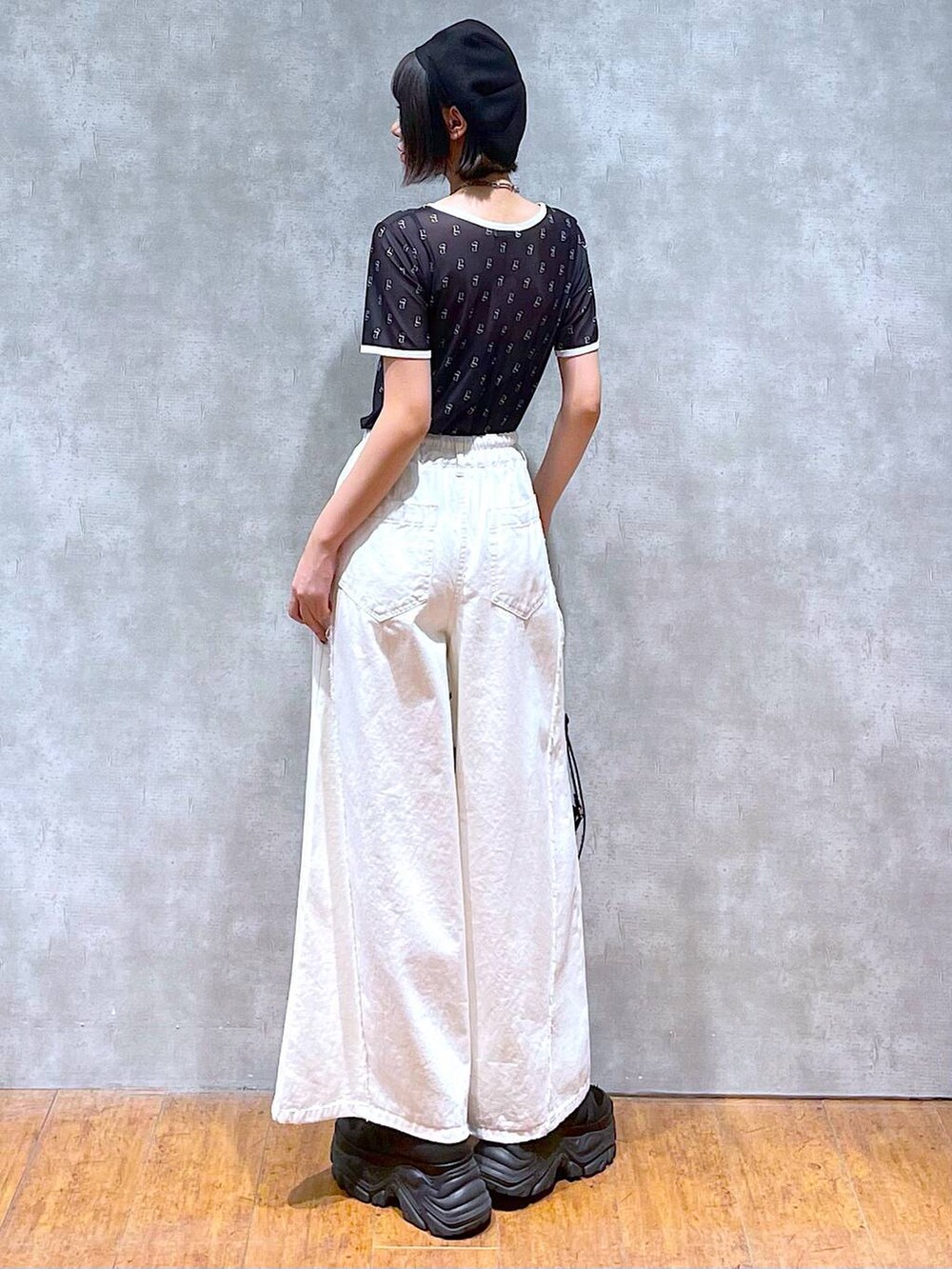 ブラック系のスニーカー、ブラック系のキャミソール、ホワイト系のデニムパンツを着用したレディースの夏コーディネートの3枚目の写真