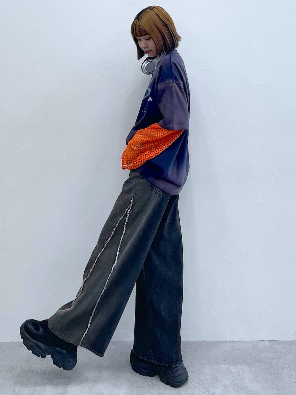 ブラック系のスニーカー、オレンジ系のTシャツ/カットソー、ブラック系のデニムパンツを着用したレディースの夏コーディネートの2枚目の写真