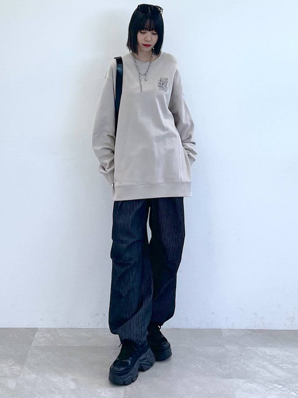 ブラック系のスニーカー、ブラック系のショルダーバッグ、ブラック系のデニムパンツを着用したレディースの秋コーディネートの6枚目の写真