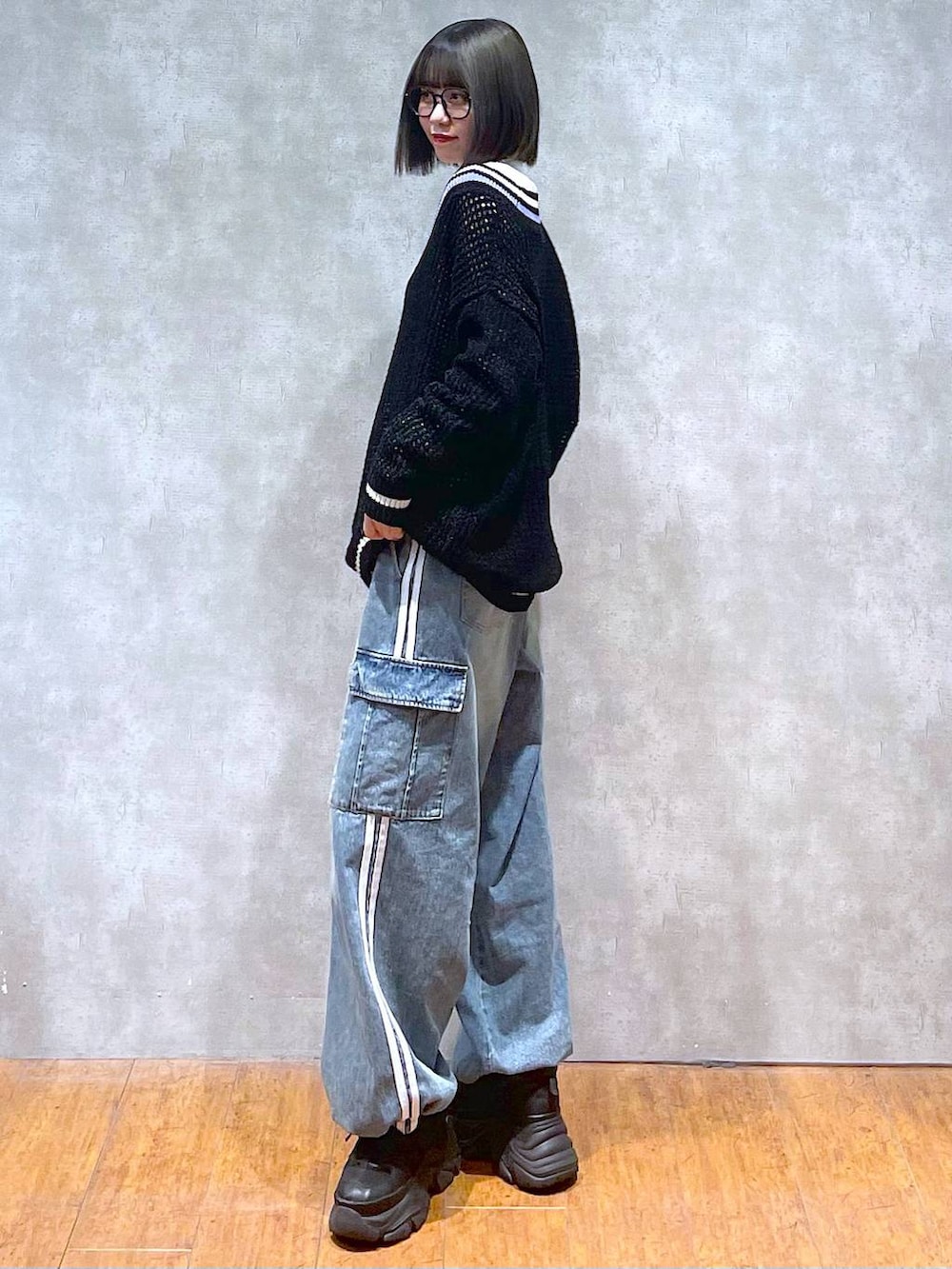 ブラック系のスニーカー、ブルー系のデニムパンツ、ブラック系のニット/セーターを着用したレディースの秋コーディネートの6枚目の写真