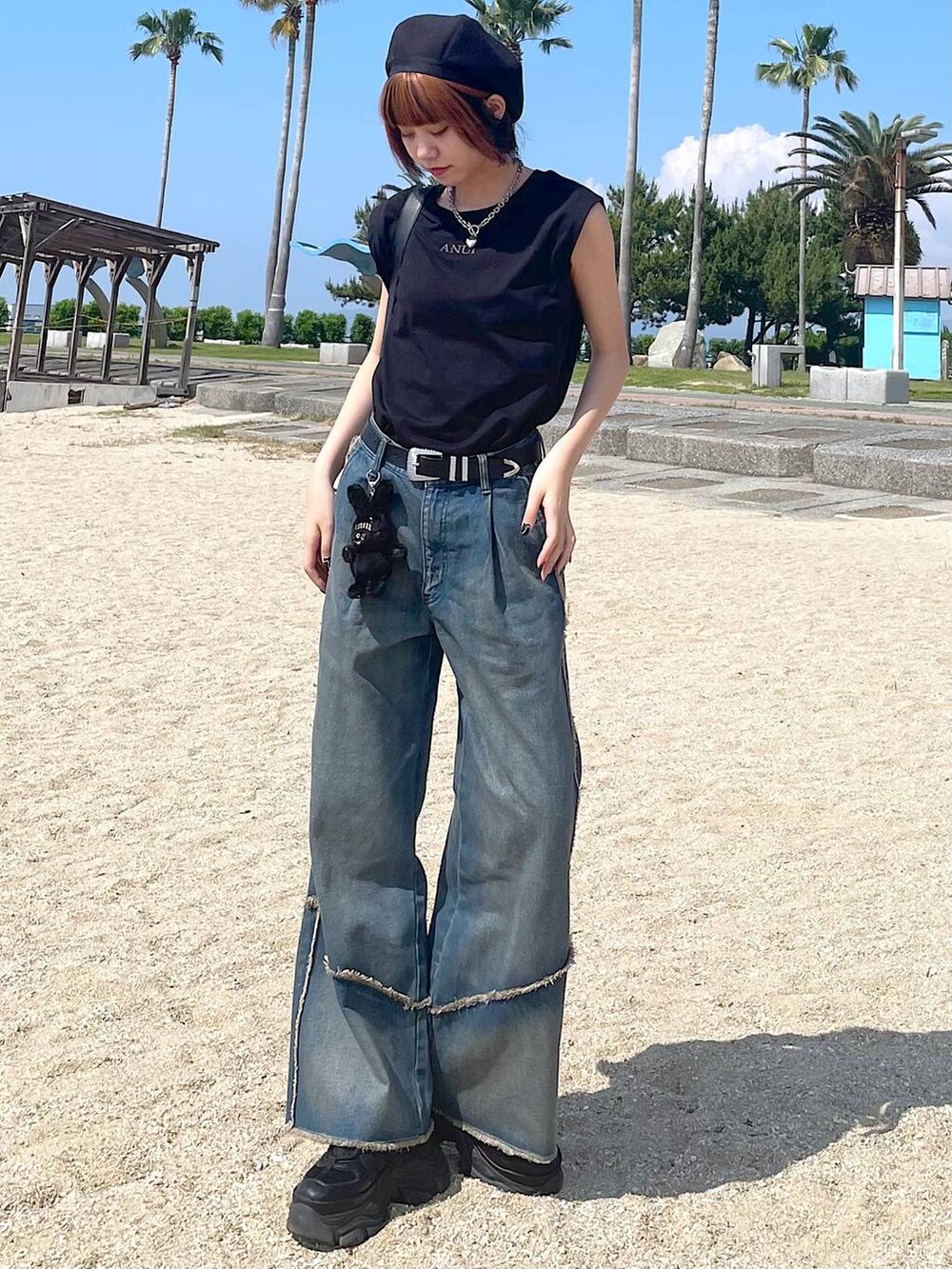 ブラック系のショルダーバッグ、ブラック系のスニーカー、オレンジ系のデニムパンツを着用したレディースの夏コーディネートの4枚目の写真