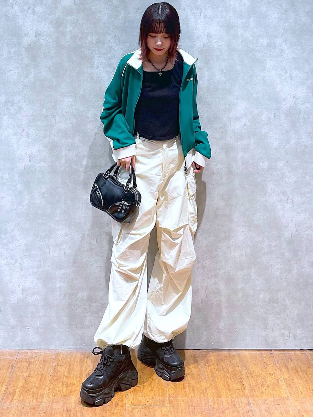 グリーン系のセットアップ、ブラック系のボストンバッグ、ホワイト系のカーゴパンツを着用したレディースの春コーディネートの2枚目の写真
