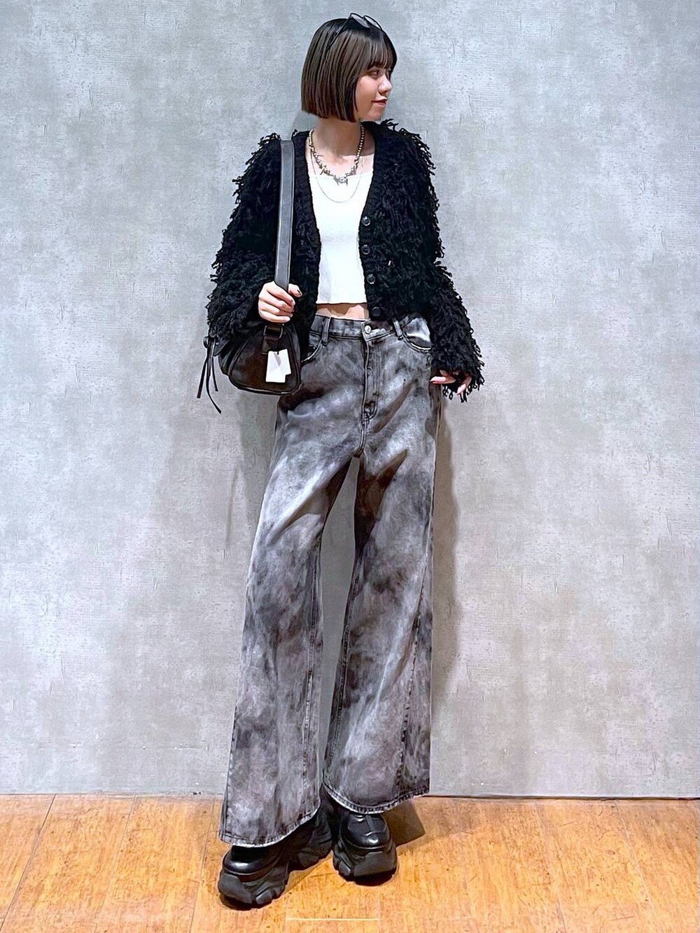 ブラック系のスニーカー、ブラック系のショルダーバッグ、ブラック系のデニムパンツを着用したレディースの秋コーディネートの6枚目の写真