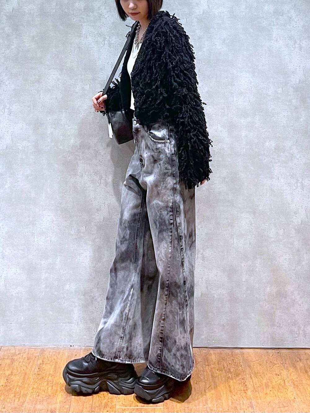 ブラック系のスニーカー、ブラック系のショルダーバッグ、ブラック系のデニムパンツを着用したレディースの秋コーディネートの7枚目の写真