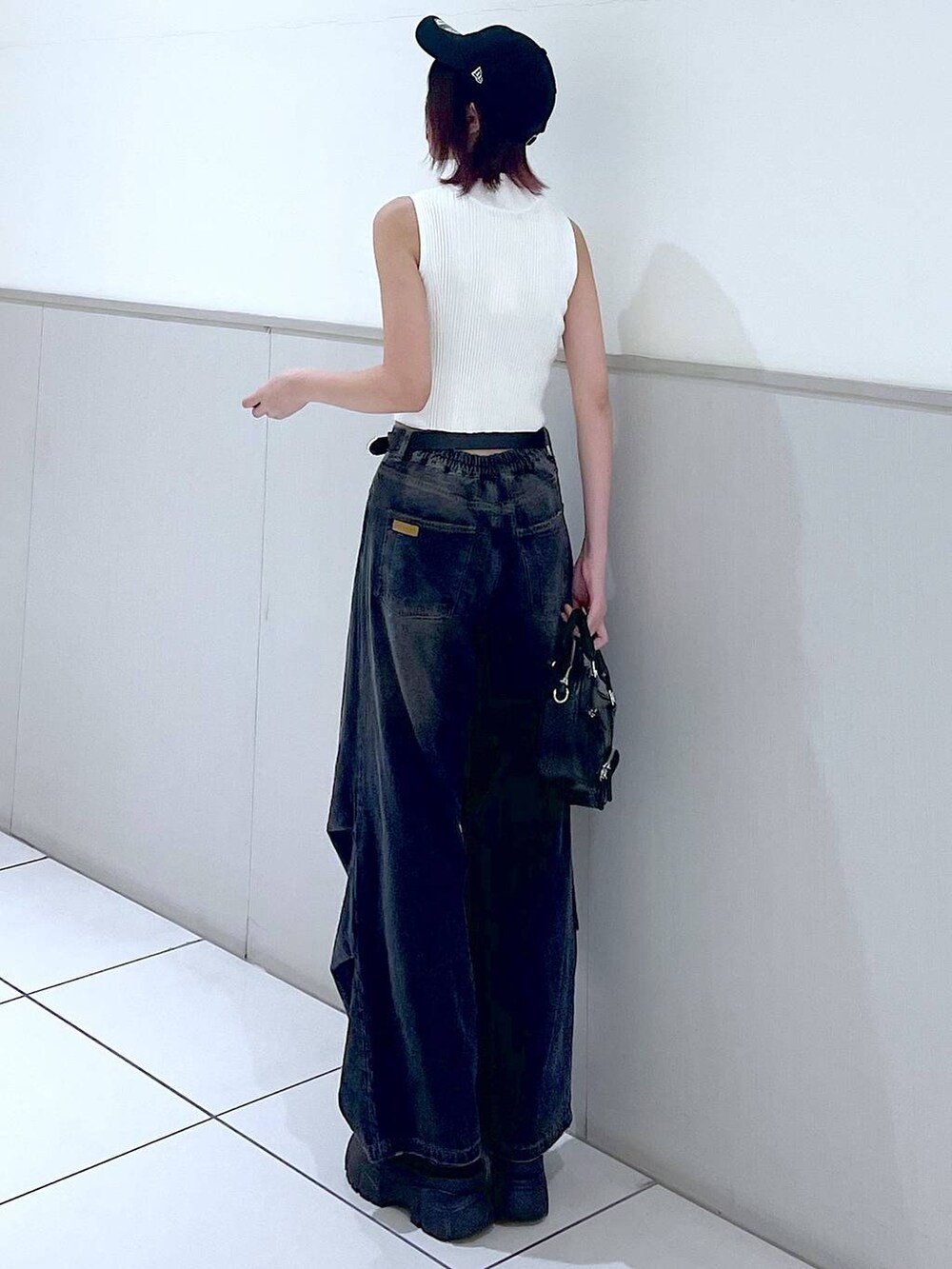 ブラック系のデニムパンツ、ホワイト系のニット/セーター、ブラック系のボストンバッグを着用したレディースの春コーディネートの6枚目の写真