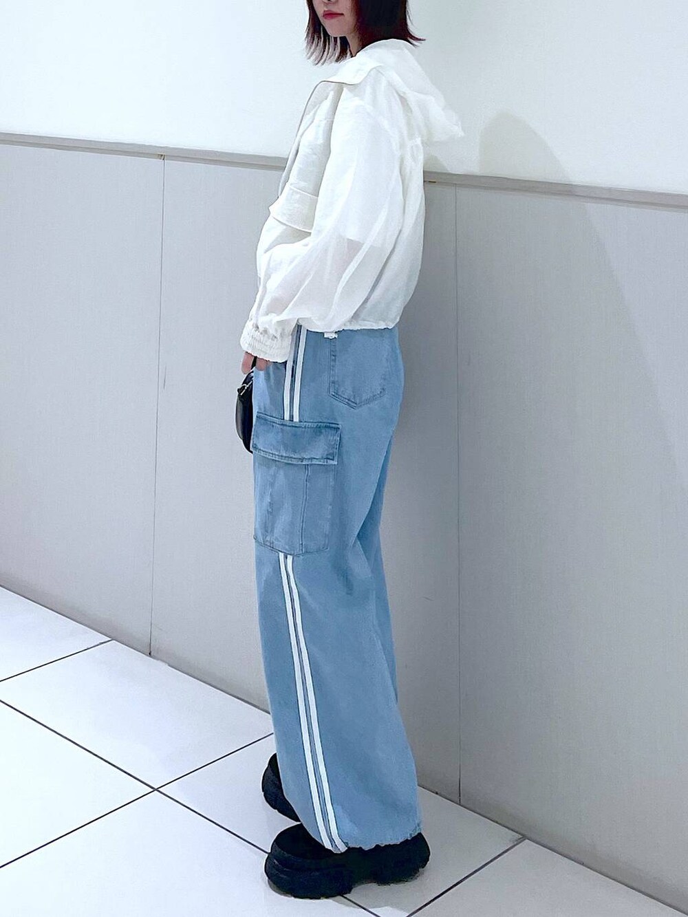 ホワイト系のブルゾン、ブルー系のデニムパンツ、ブラック系のボストンバッグを着用したレディースの春コーディネートの4枚目の写真