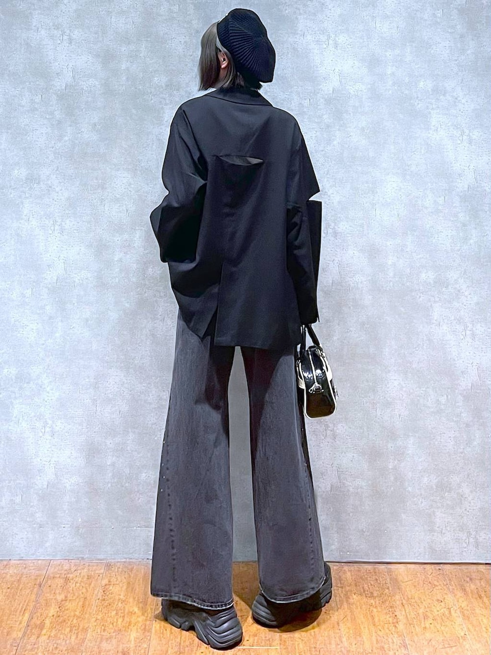 ブラック系のスニーカー、ブラック系のデニムパンツ、ブラック系のショルダーバッグを着用したレディースの秋コーディネートの5枚目の写真