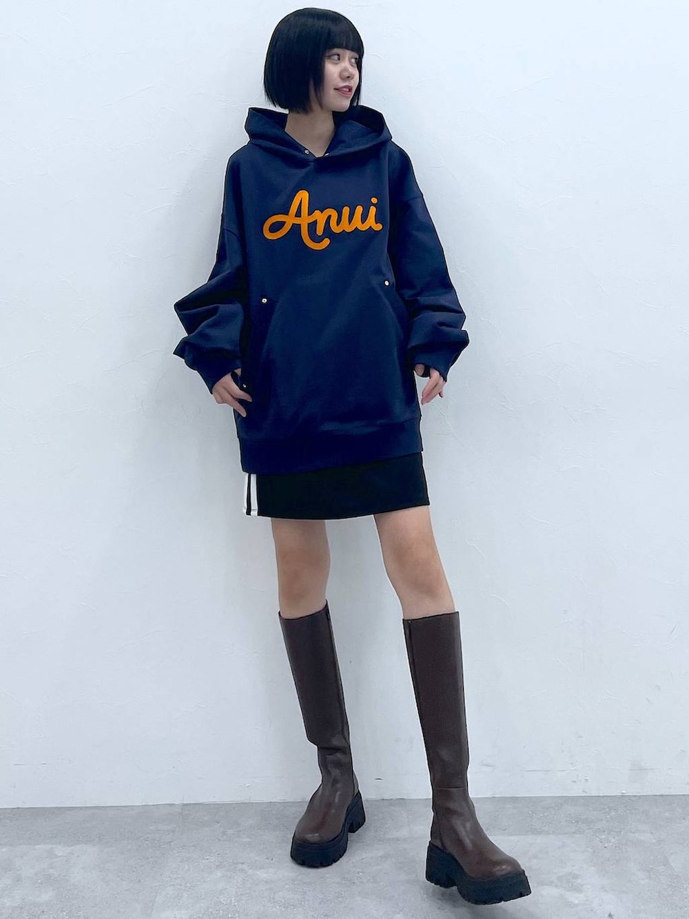 ブルー系のパーカー、ブラウン系のブーツ、ブラック系のスカートを着用したレディースの冬コーディネートの5枚目の写真