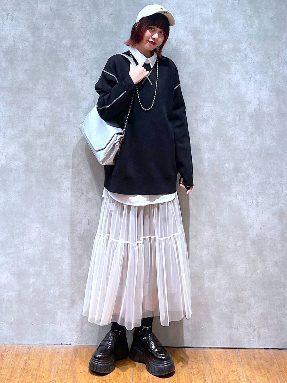 シルバー系のショルダーバッグ、ホワイト系のシャツ/ブラウス、ブラック系のニット/セーターを着用したレディースの春コーディネートの2枚目の写真