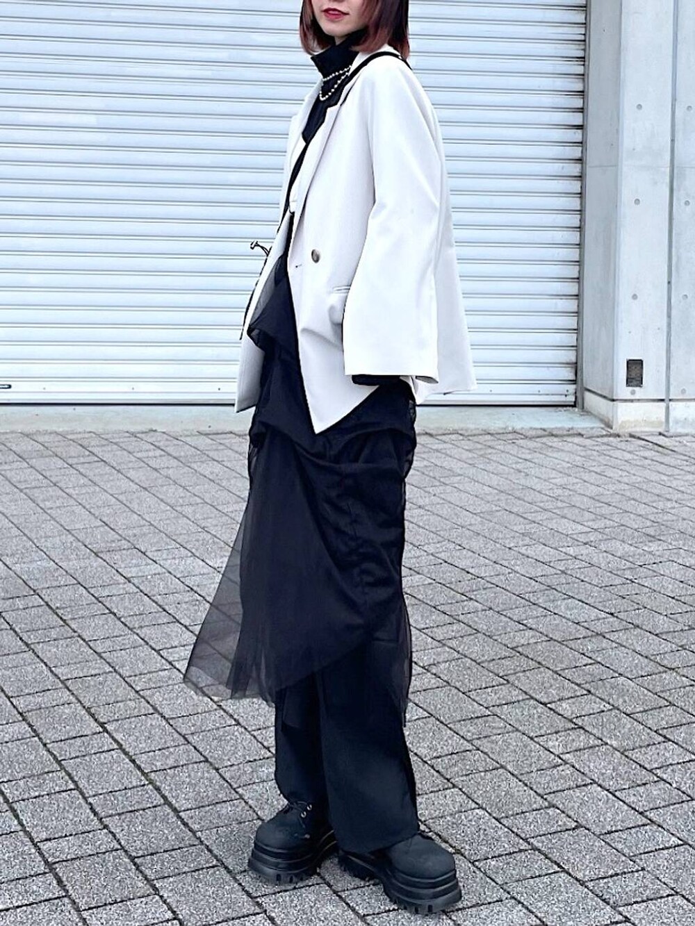 ブラック系のショルダーバッグ、ブラック系のナイロンジャケット、ブラック系のスカートを着用したレディースの春コーディネートの7枚目の写真