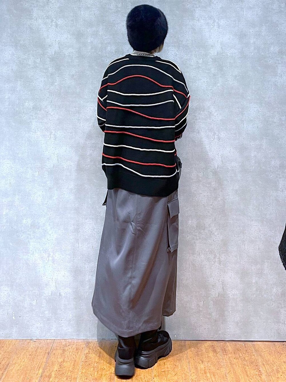 グレー系のスカート、ベージュ系のTシャツ/カットソー、ブラック系のニット/セーターを着用したレディースの冬コーディネートの4枚目の写真