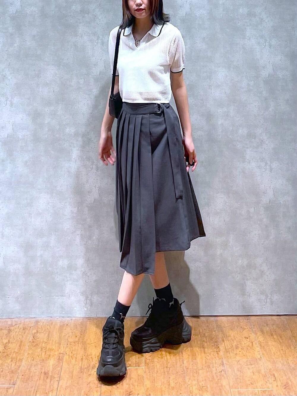 ブラック系のスニーカー、グレー系のスカート、ホワイト系のキャミソールを着用したレディースの夏コーディネートの3枚目の写真