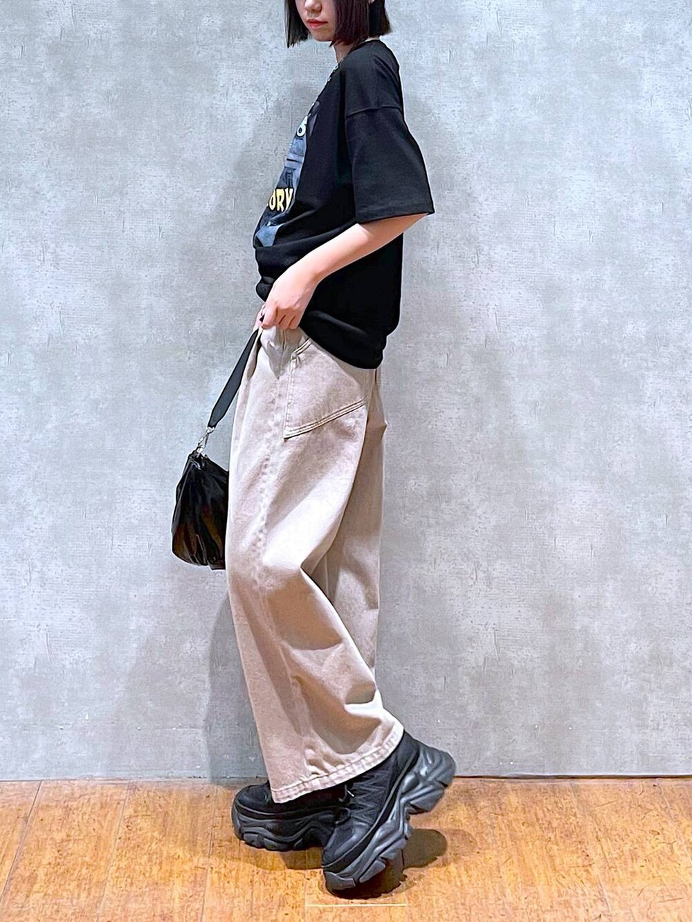 ブラック系のスニーカー、ブラック系のショルダーバッグ、ベージュ系のデニムパンツを着用したレディースの夏コーディネートの4枚目の写真