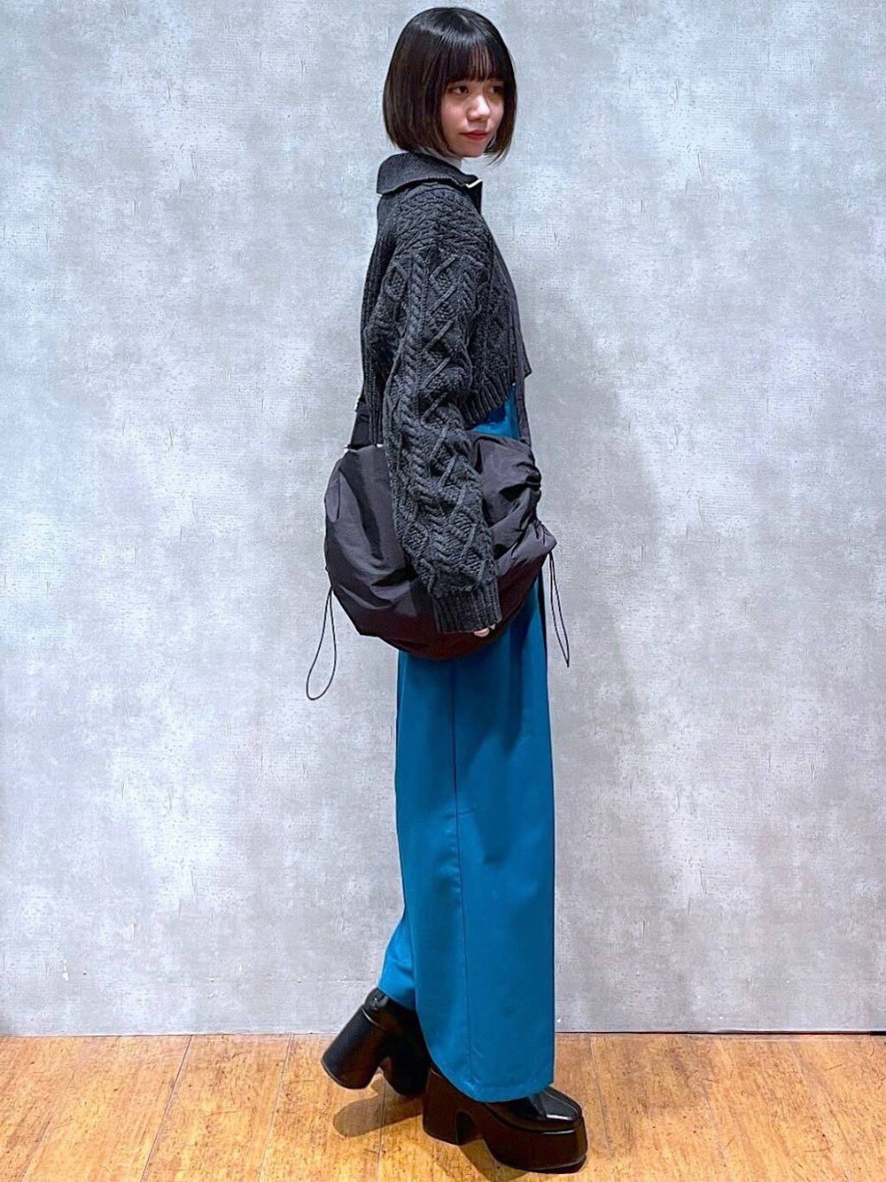 ホワイト系のニット/セーター、ブラック系のブーツ、ブラック系のショルダーバッグを着用したレディースの冬コーディネートの2枚目の写真