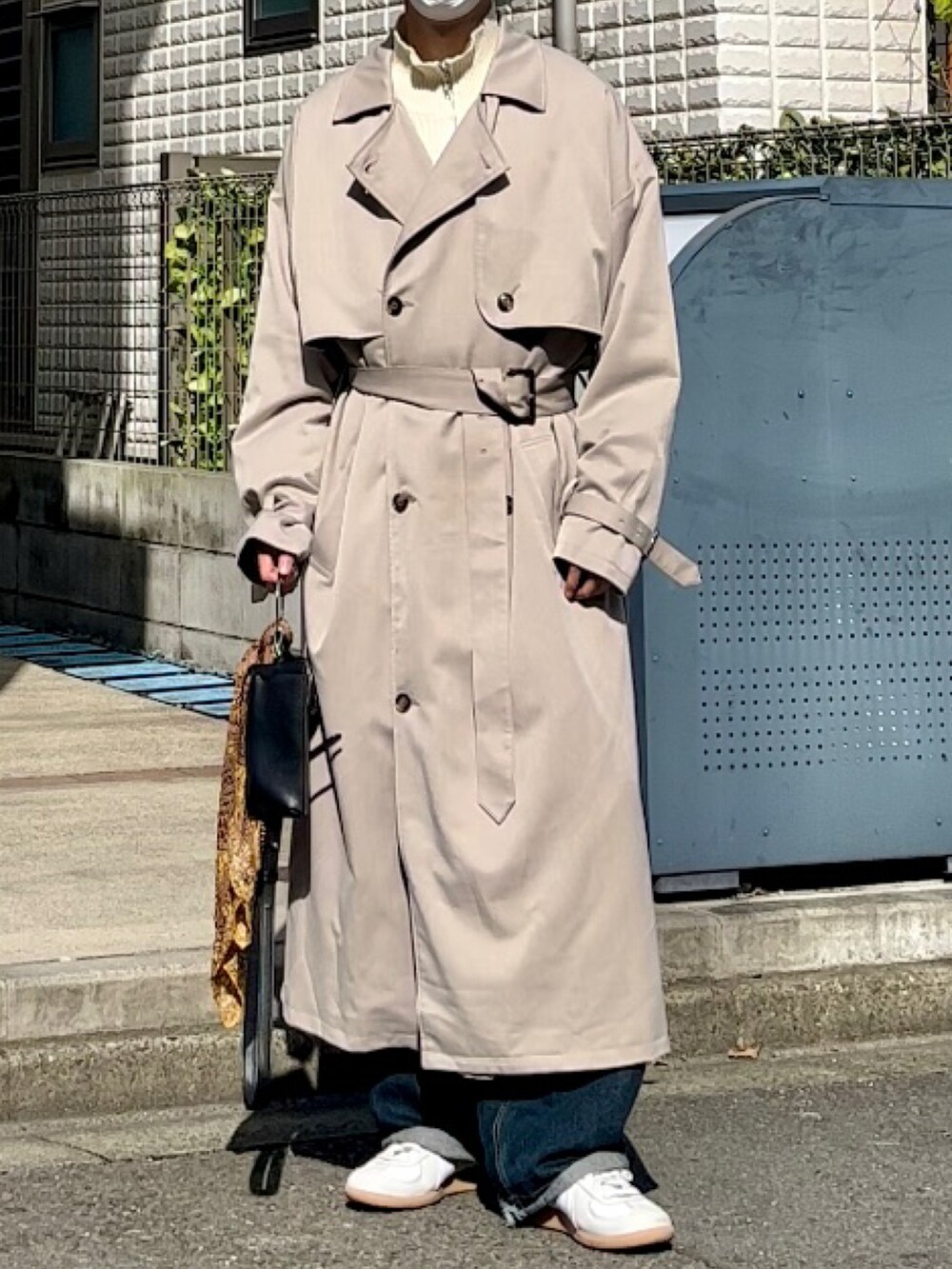 ベージュ系のトレンチコート、ブルー系のデニムパンツを着用したメンズの秋コーディネートの3枚目の写真