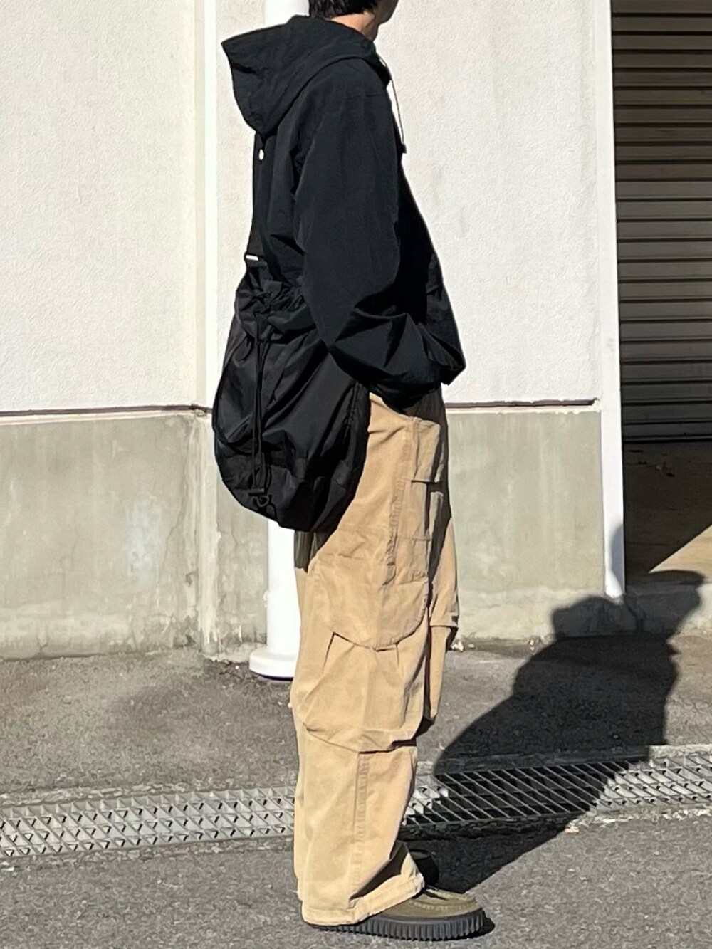 グリーン系のモカシン/デッキシューズ、ベージュ系のカーゴパンツ、ブラック系のショルダーバッグを着用したメンズの冬コーディネートの2枚目の写真