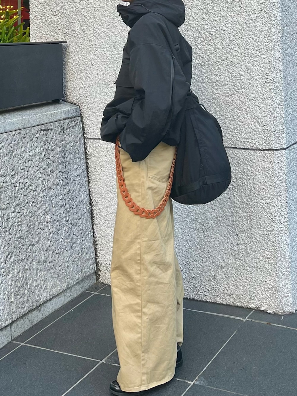 ベージュ系のチノパンツ、ブラック系のナイロンジャケット、ブラック系のショルダーバッグを着用したメンズの秋コーディネートの3枚目の写真