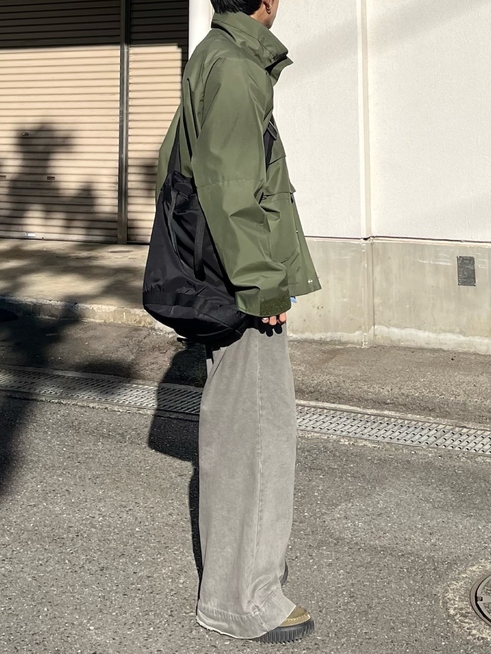 グレー系のデニムパンツ、グリーン系のモカシン/デッキシューズ、グリーン系のマウンテンパーカーを着用したメンズの秋コーディネートの2枚目の写真