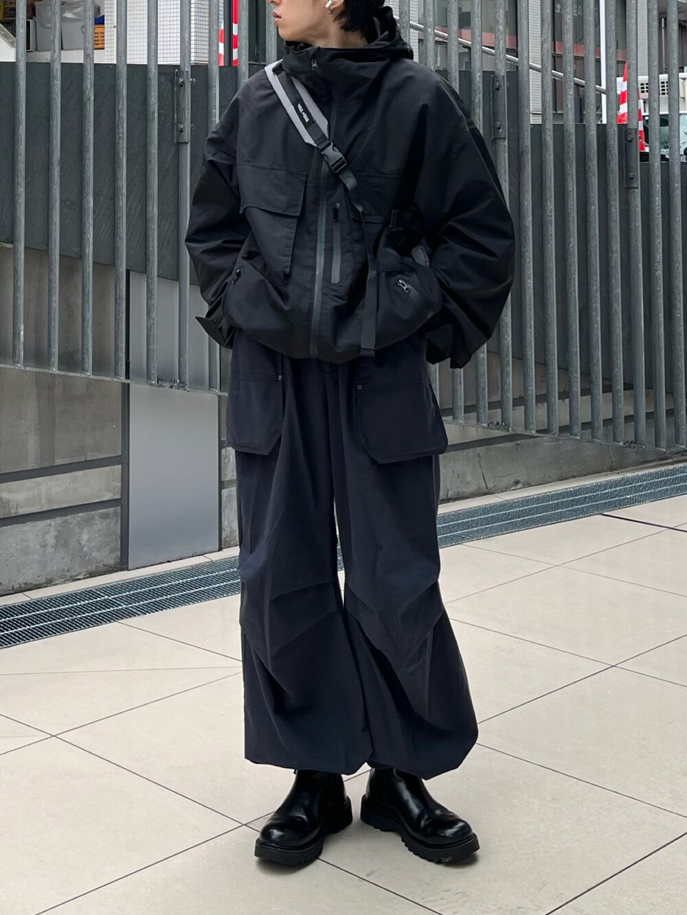 ブラック系のマウンテンパーカー、ブルー系のカーゴパンツ、ブラック系のブーツを着用したメンズの春コーディネートの3枚目の写真