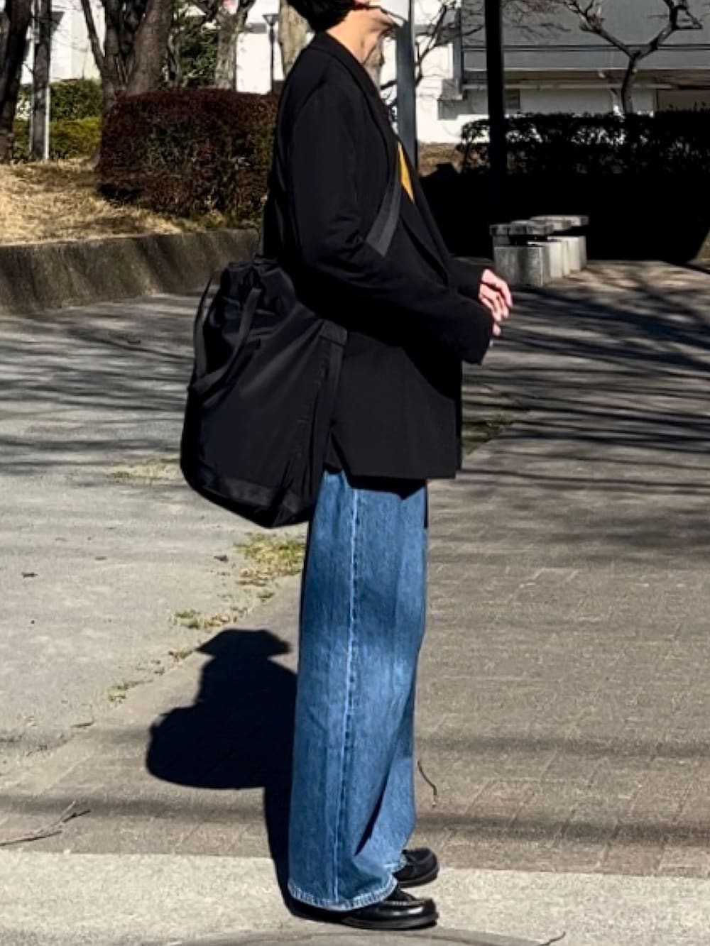 イエロー系のカーディガン/ボレロ、ブラック系のテーラードジャケット、ブルー系のデニムパンツを着用したメンズの春コーディネートの3枚目の写真