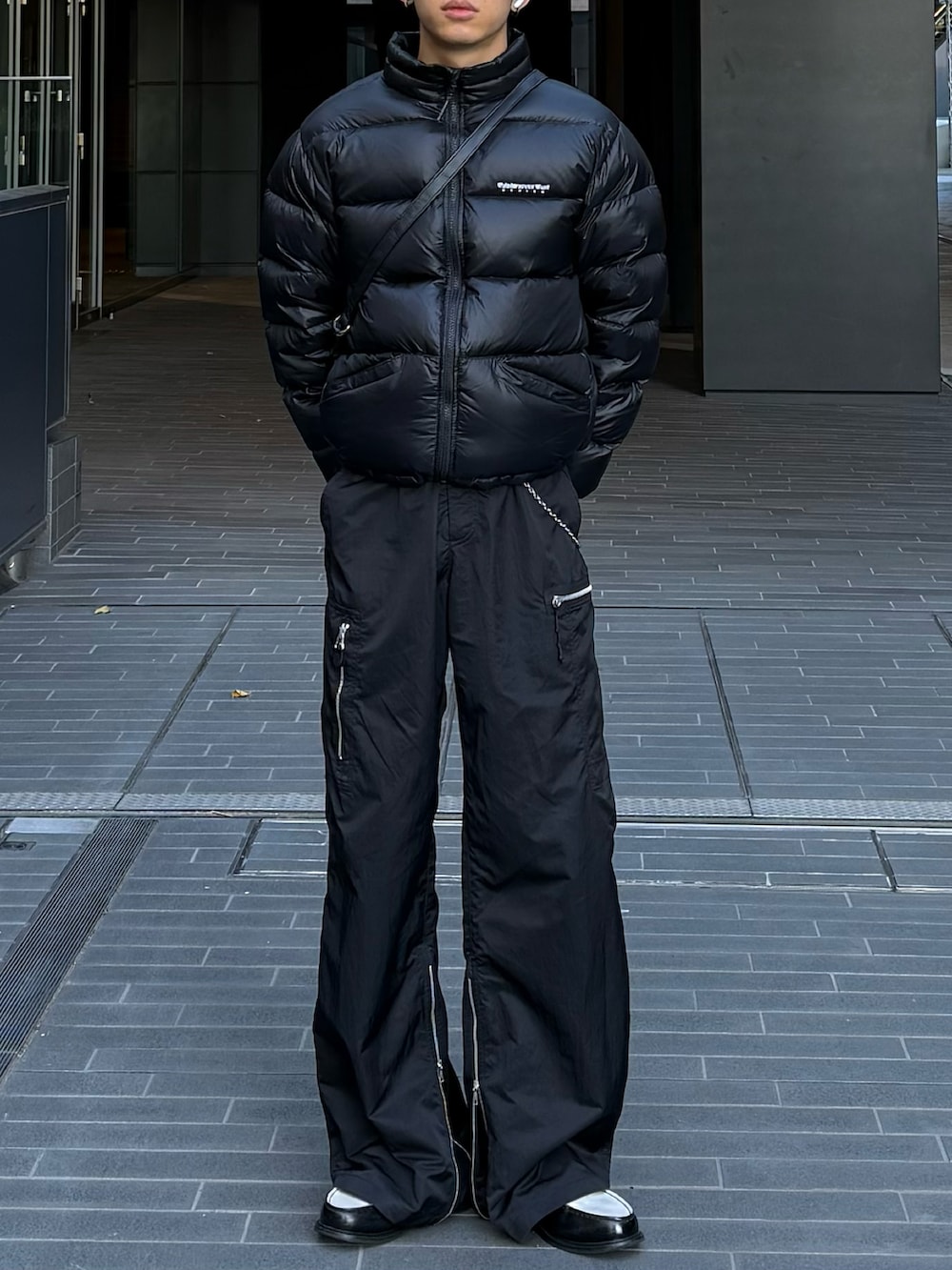 ブラック系のダウンジャケット/コート、ブラック系のローファー、ブラック系のショルダーバッグを着用したメンズの冬コーディネートの2枚目の写真