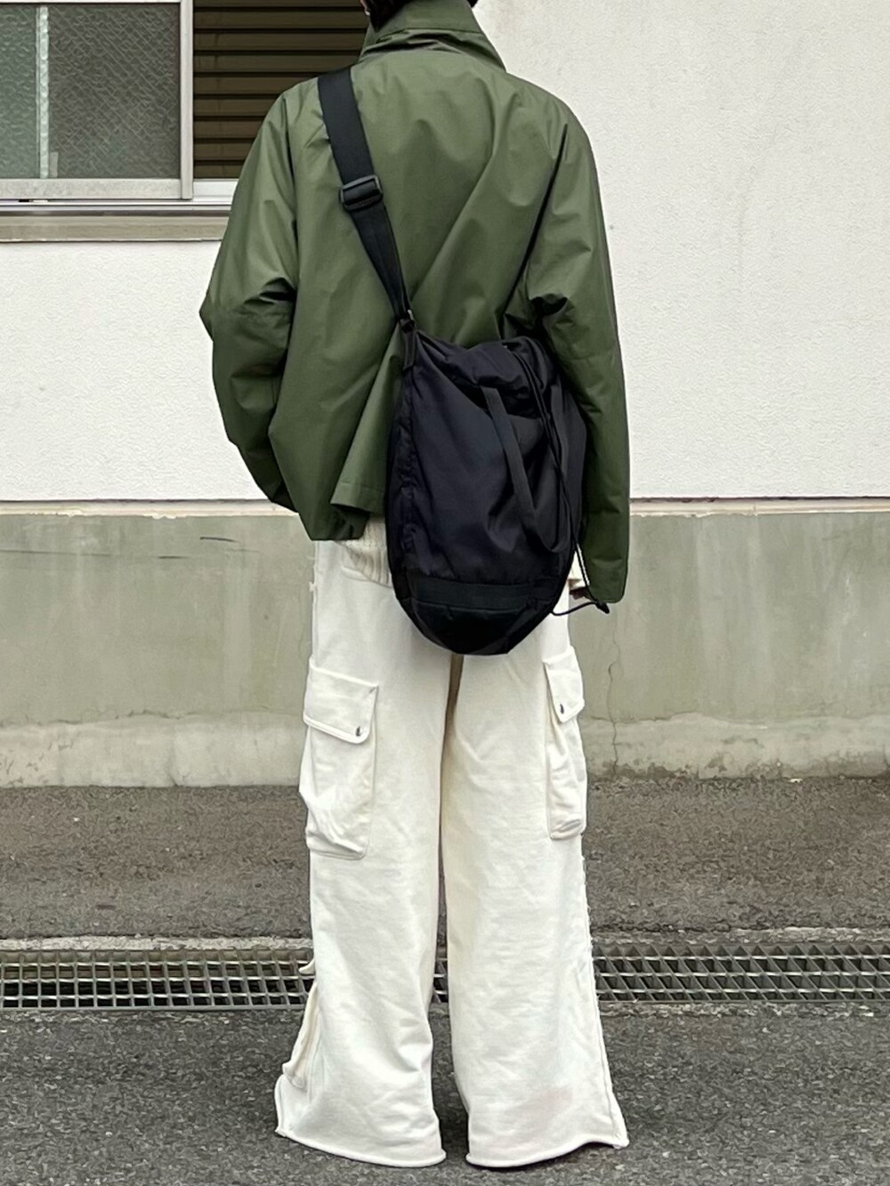 グリーン系のマウンテンパーカー、ホワイト系のスウェットパンツ、グリーン系のモカシン/デッキシューズを着用したメンズの冬コーディネートの3枚目の写真