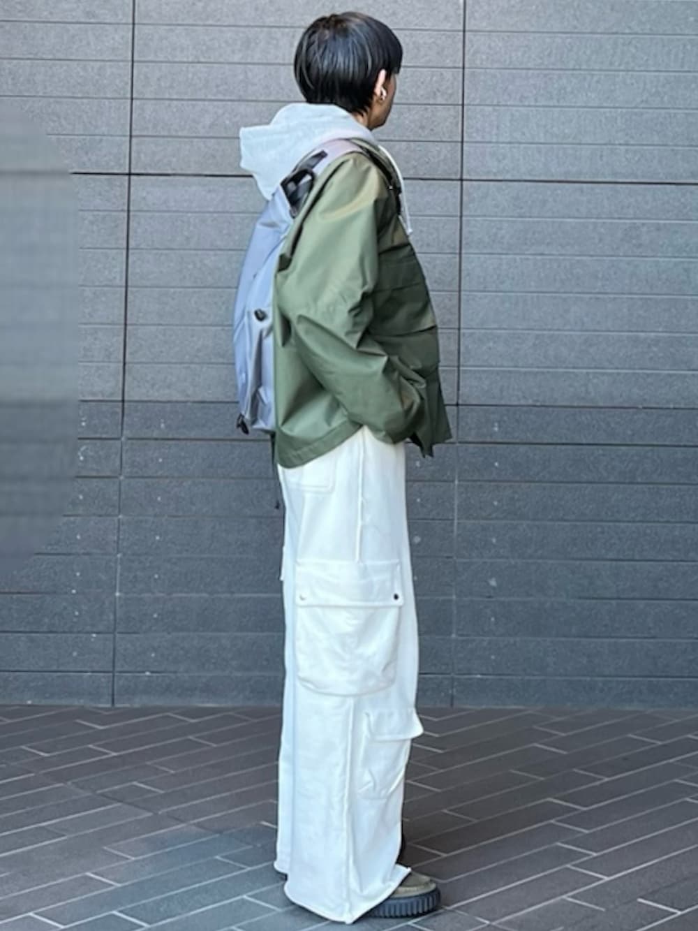 グリーン系のマウンテンパーカー、グレー系のパーカー、ホワイト系のスウェットパンツを着用したメンズの春コーディネートの2枚目の写真