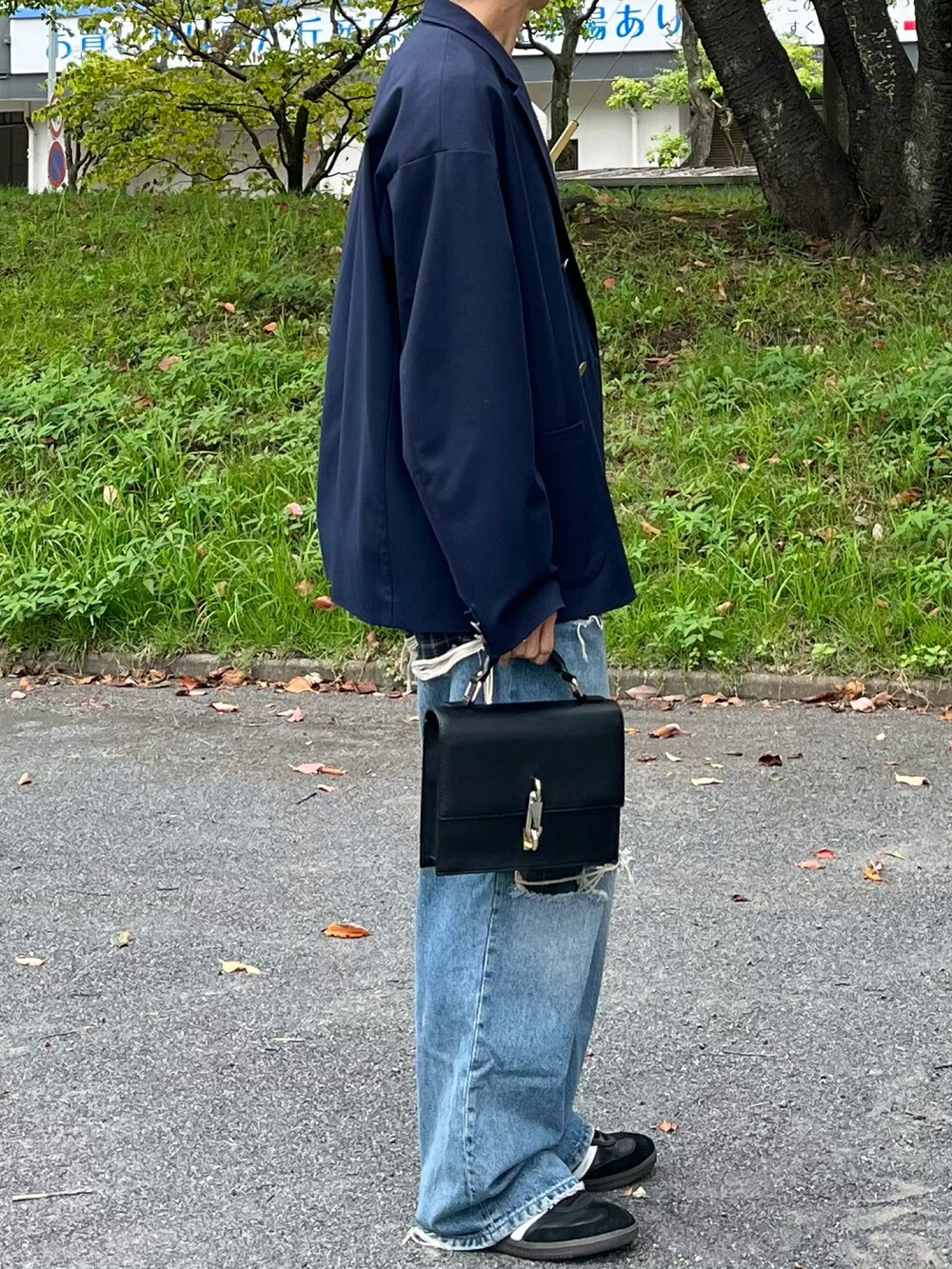 ブルー系のテーラードジャケット、ホワイト系のベスト、ブルー系のデニムパンツを着用したメンズの秋コーディネートの2枚目の写真