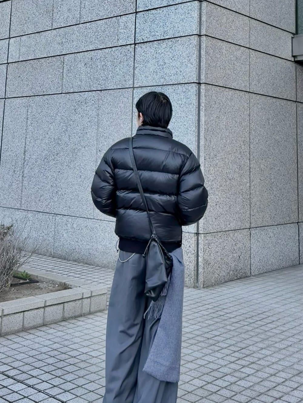 ブラック系のダウンジャケット/コート、グレー系のスラックス、ブラック系のショルダーバッグを着用したメンズの冬コーディネートの3枚目の写真