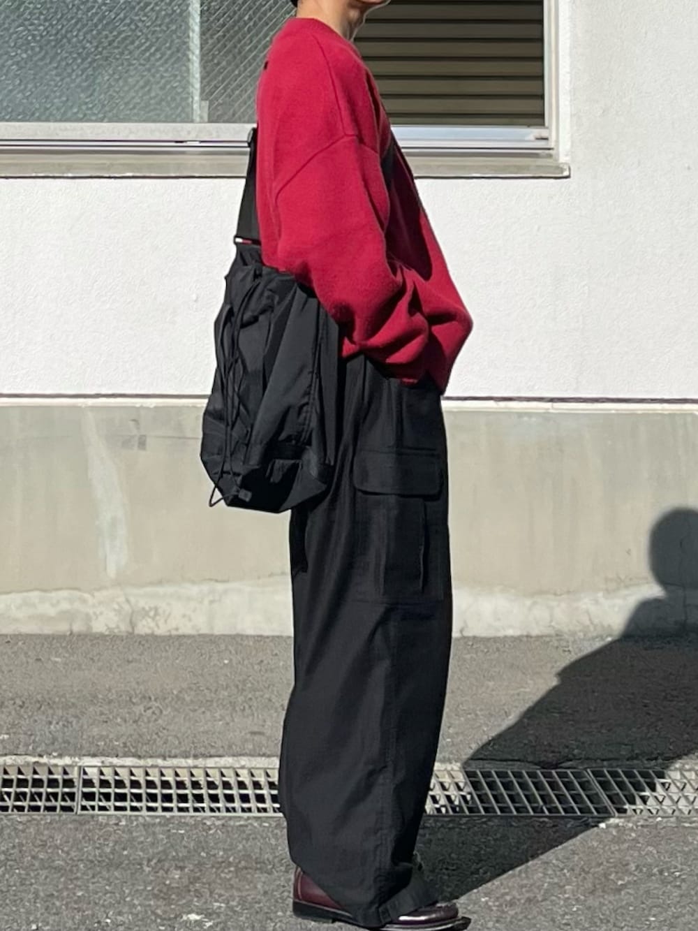 ブラック系のカーゴパンツ、レッド系のカーディガン/ボレロ、ブラウン系のローファーを着用したメンズの冬コーディネートの2枚目の写真