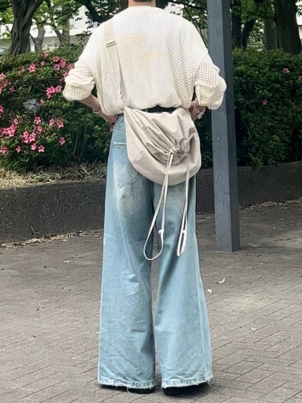 ブルー系のデニムパンツ、ホワイト系のニット/セーター、ベージュ系のショルダーバッグを着用したメンズの夏コーディネートの3枚目の写真