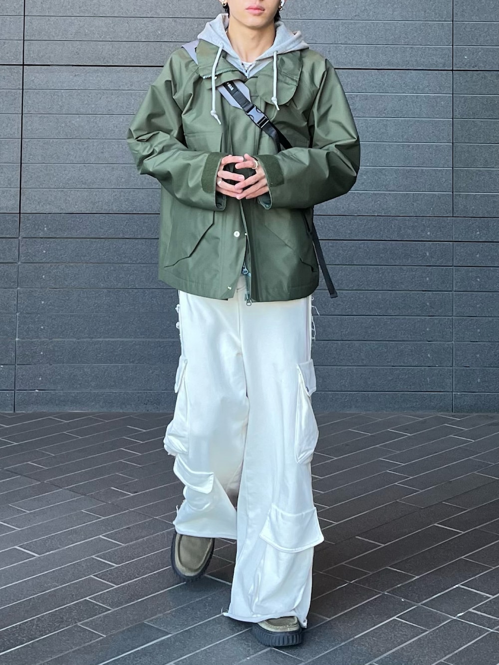 グリーン系のマウンテンパーカー、グレー系のパーカー、ホワイト系のスウェットパンツを着用したメンズの春コーディネートの3枚目の写真