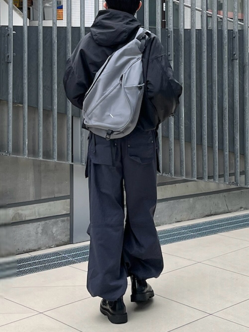 ブラック系のマウンテンパーカー、ブルー系のカーゴパンツ、ブラック系のブーツを着用したメンズの春コーディネートの2枚目の写真