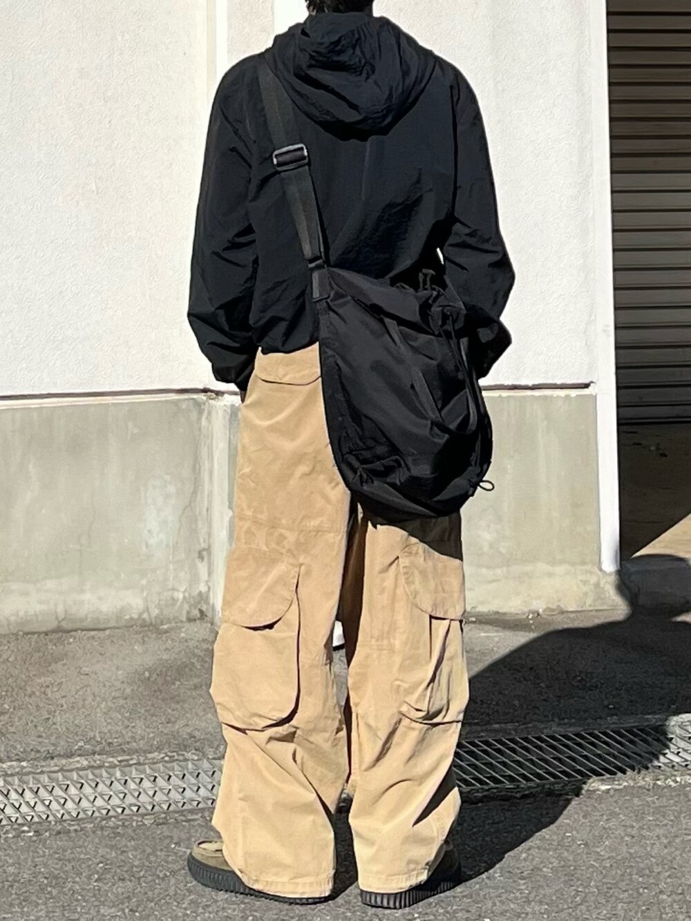 グリーン系のモカシン/デッキシューズ、ベージュ系のカーゴパンツ、ブラック系のショルダーバッグを着用したメンズの冬コーディネートの3枚目の写真
