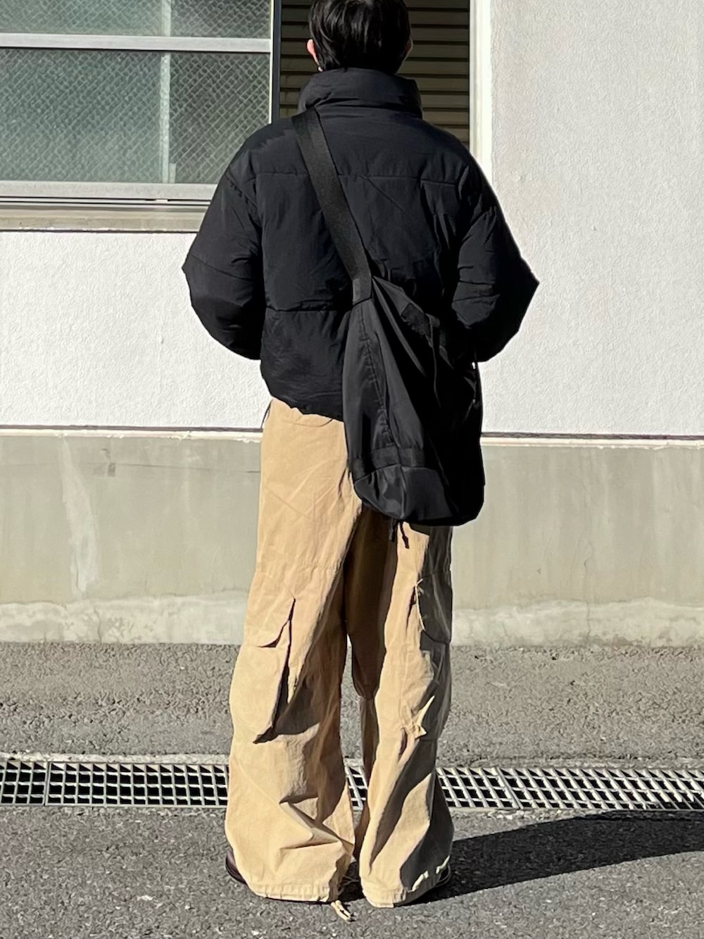 ブラック系のダウンジャケット/コート、ベージュ系のカーゴパンツ、ブラウン系のローファーを着用したメンズの冬コーディネートの3枚目の写真