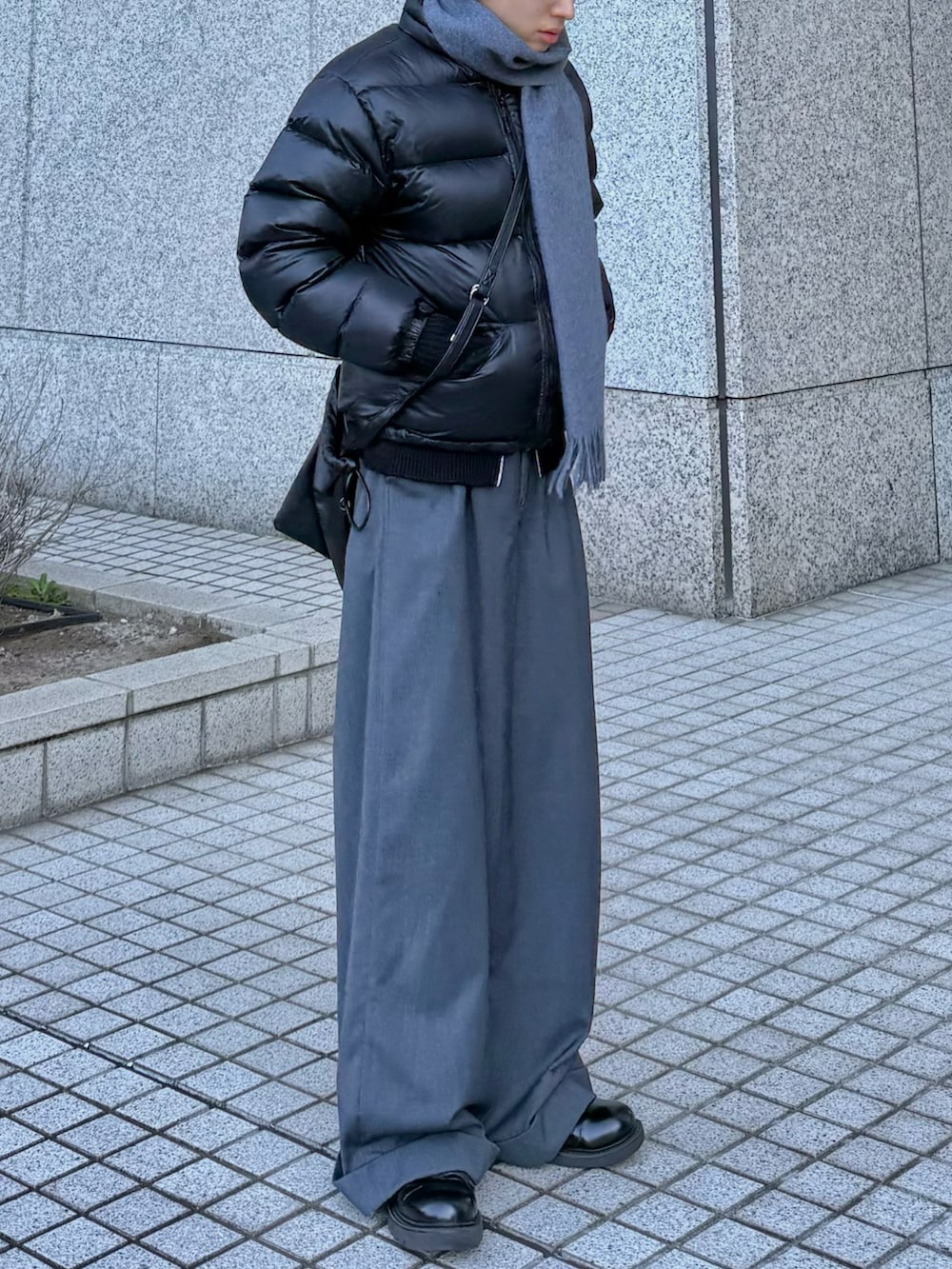 ブラック系のダウンジャケット/コート、グレー系のスラックス、ブラック系のショルダーバッグを着用したメンズの冬コーディネートの2枚目の写真