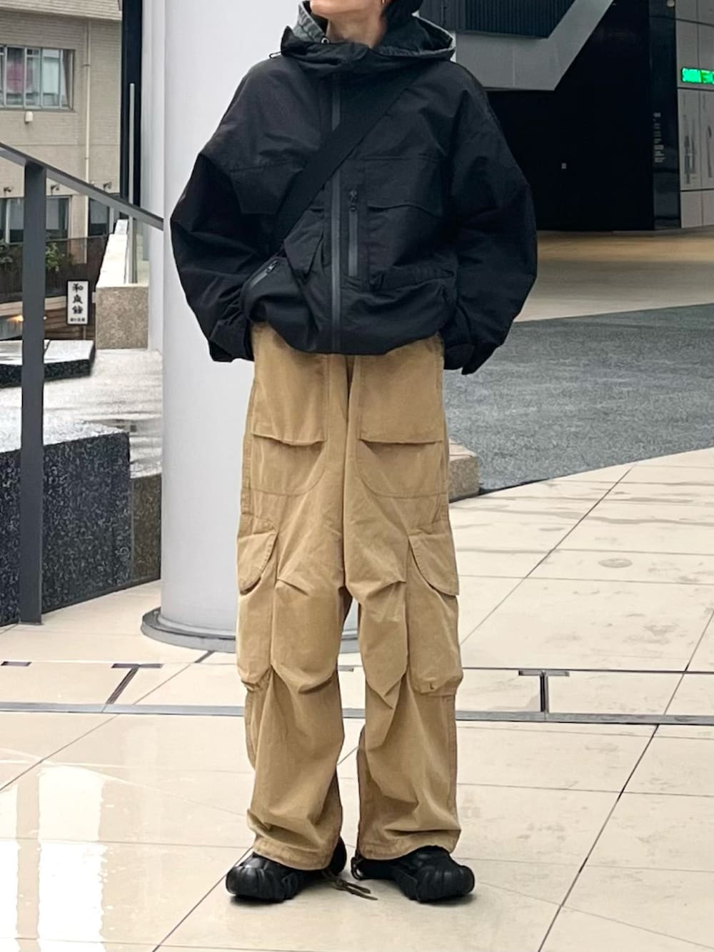 ベージュ系のカーゴパンツ、ブラック系のパーカー、ブラック系のマウンテンパーカーを着用したメンズの冬コーディネートの4枚目の写真