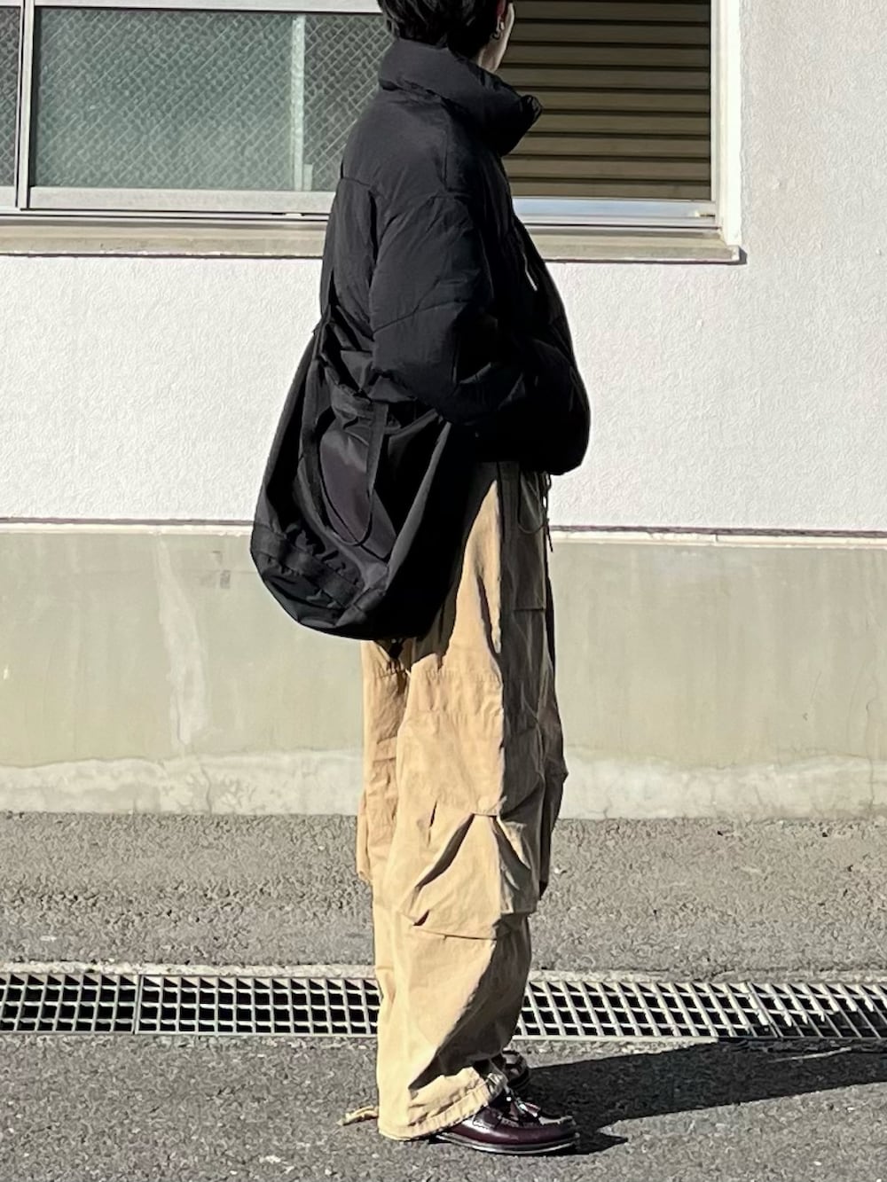 ブラック系のダウンジャケット/コート、ベージュ系のカーゴパンツ、ブラウン系のローファーを着用したメンズの冬コーディネートの2枚目の写真