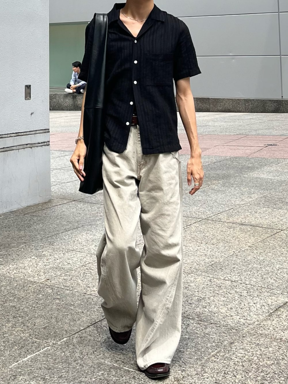 ベージュ系のデニムパンツ、ブラック系のショルダーバッグ、ブラウン系のローファーを着用したメンズの夏コーディネートの2枚目の写真