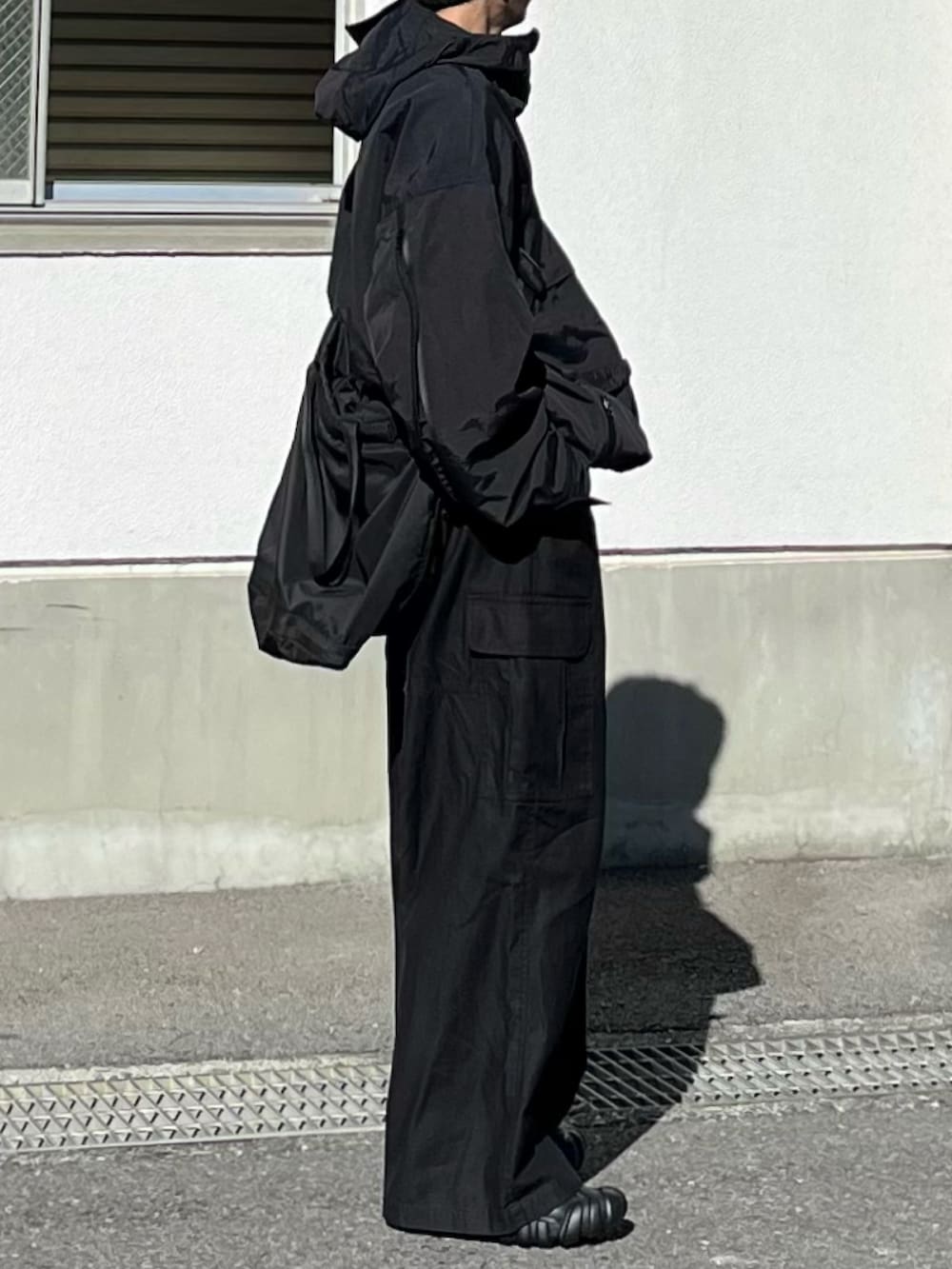 ブラック系のマウンテンパーカー、ブラック系のカーゴパンツ、ブラック系のスニーカーを着用したメンズの冬コーディネートの2枚目の写真