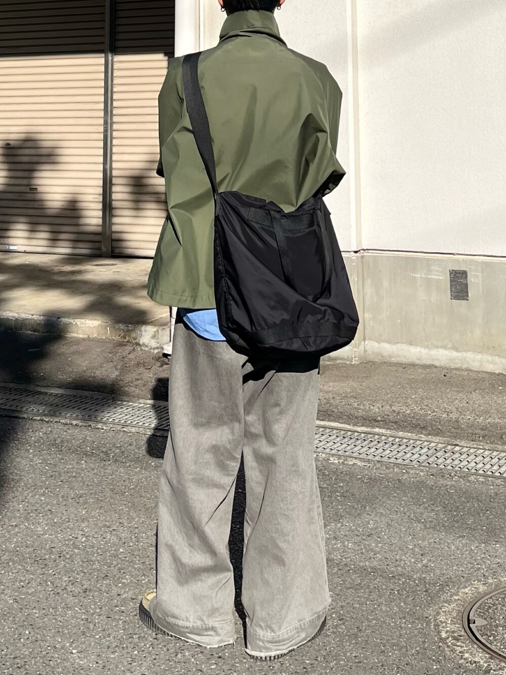 グレー系のデニムパンツ、グリーン系のモカシン/デッキシューズ、グリーン系のマウンテンパーカーを着用したメンズの秋コーディネートの3枚目の写真