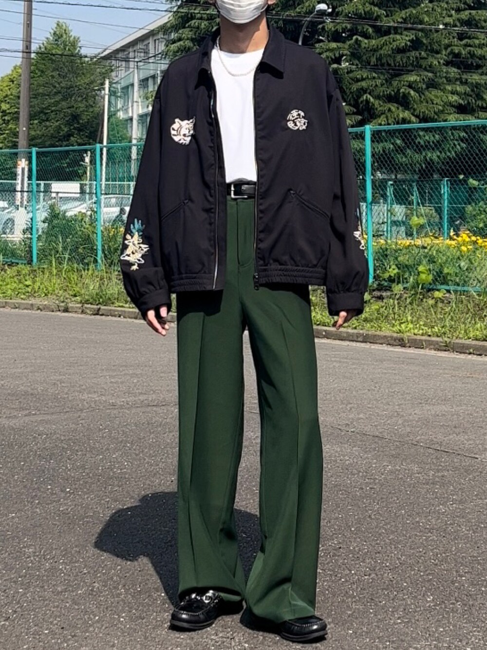 ホワイト系のTシャツ/カットソー、ブラック系のブルゾン、グリーン系のスラックスを着用したメンズの春コーディネートの2枚目の写真