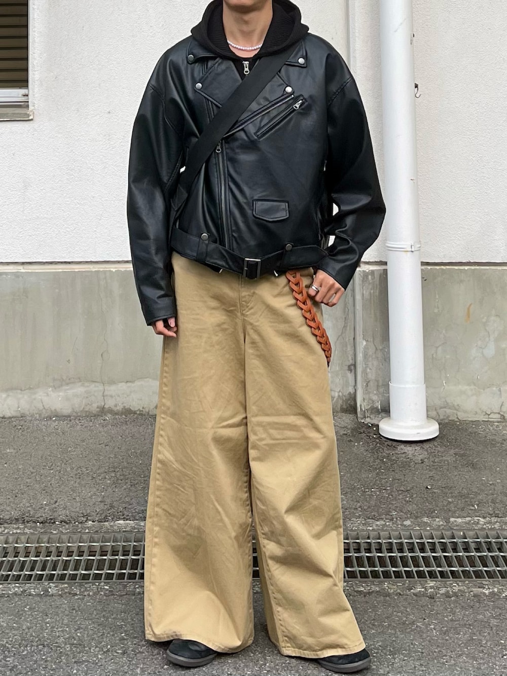 ベージュ系のチノパンツ、ブラック系のライダースジャケット、ブラック系のベストを着用したメンズの秋コーディネートの3枚目の写真