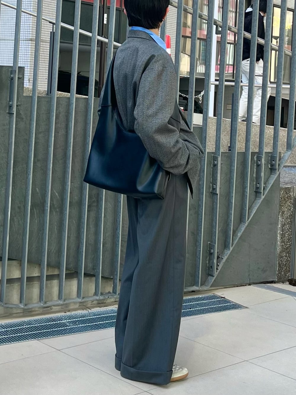 グレー系のスラックス、グレー系のテーラードジャケット、ブラック系のショルダーバッグを着用したメンズの春コーディネートの2枚目の写真