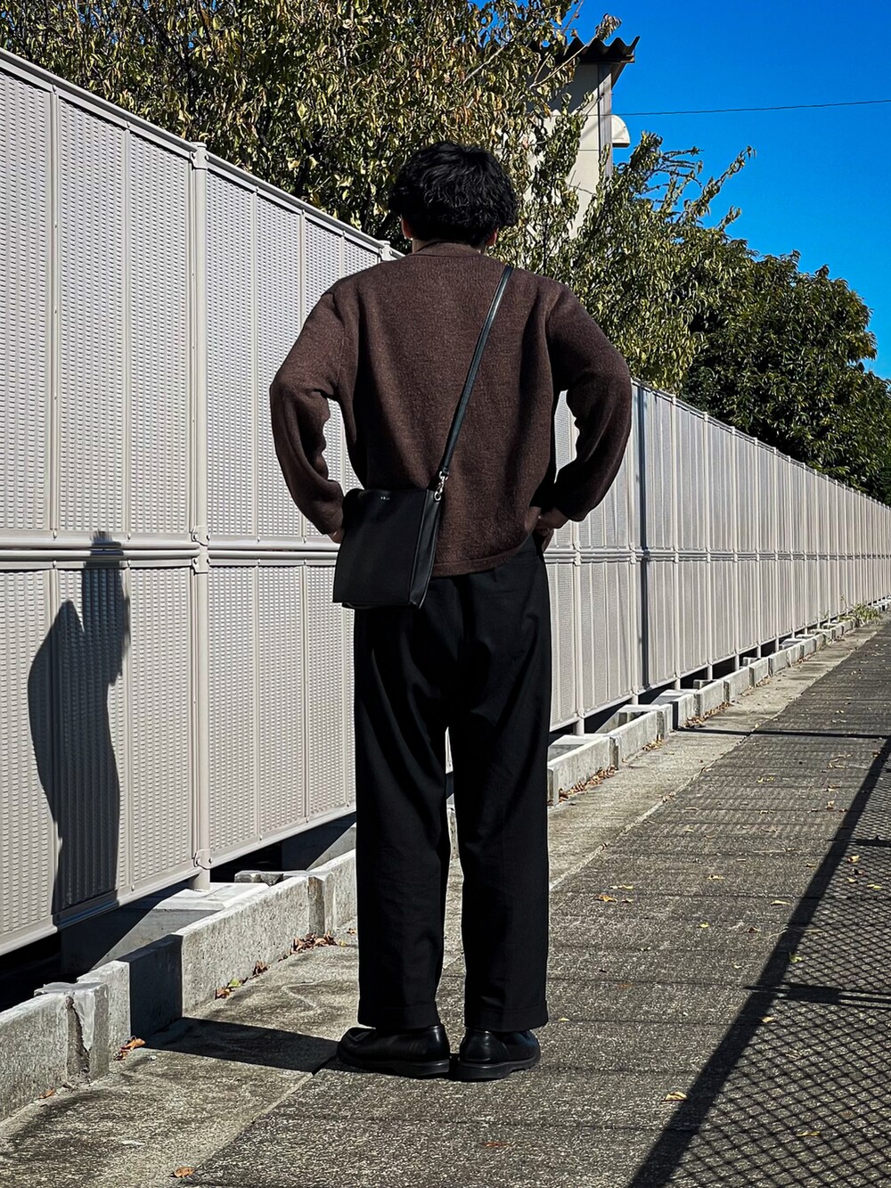 ブラウン系のカーディガン/ボレロ、グレー系のTシャツ/カットソー、ブラック系のスラックスを着用したメンズの秋コーディネートの2枚目の写真